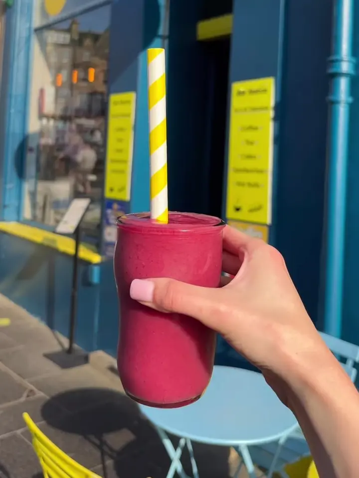 A fresh smoothie held outside the blue shopfront